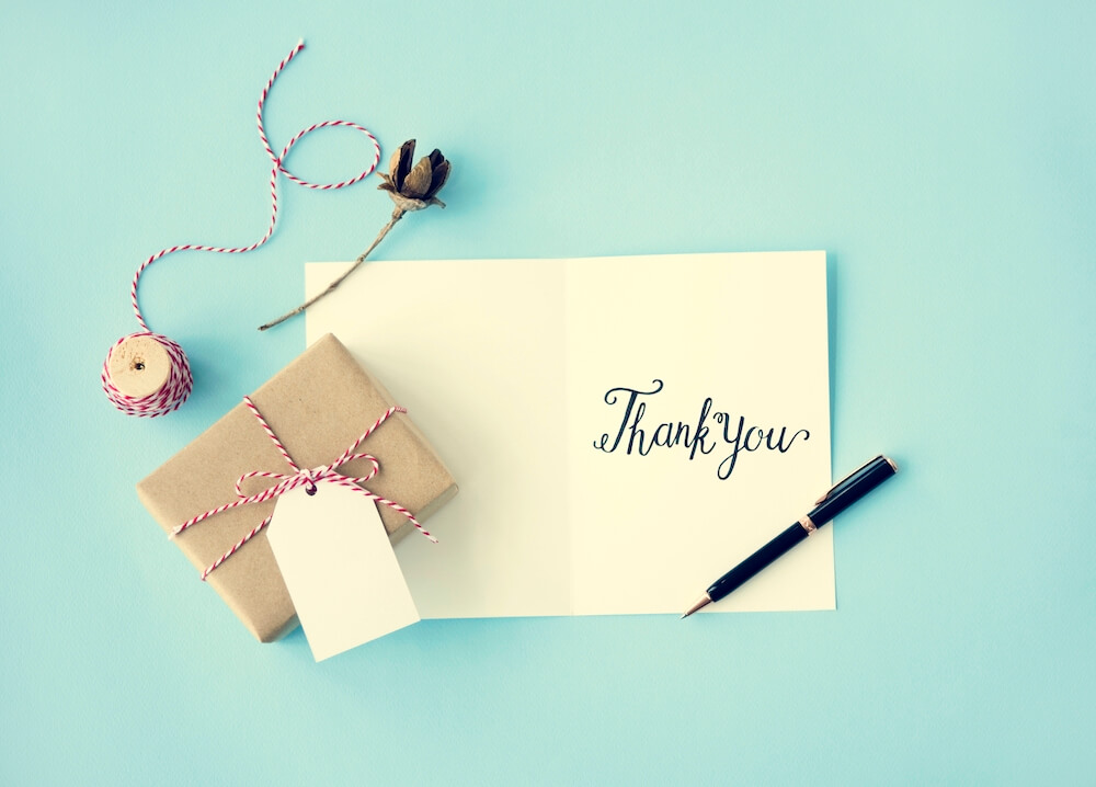 Happy graduate student with a certificate after graduation ceremony at the university. a written thank you note with a present