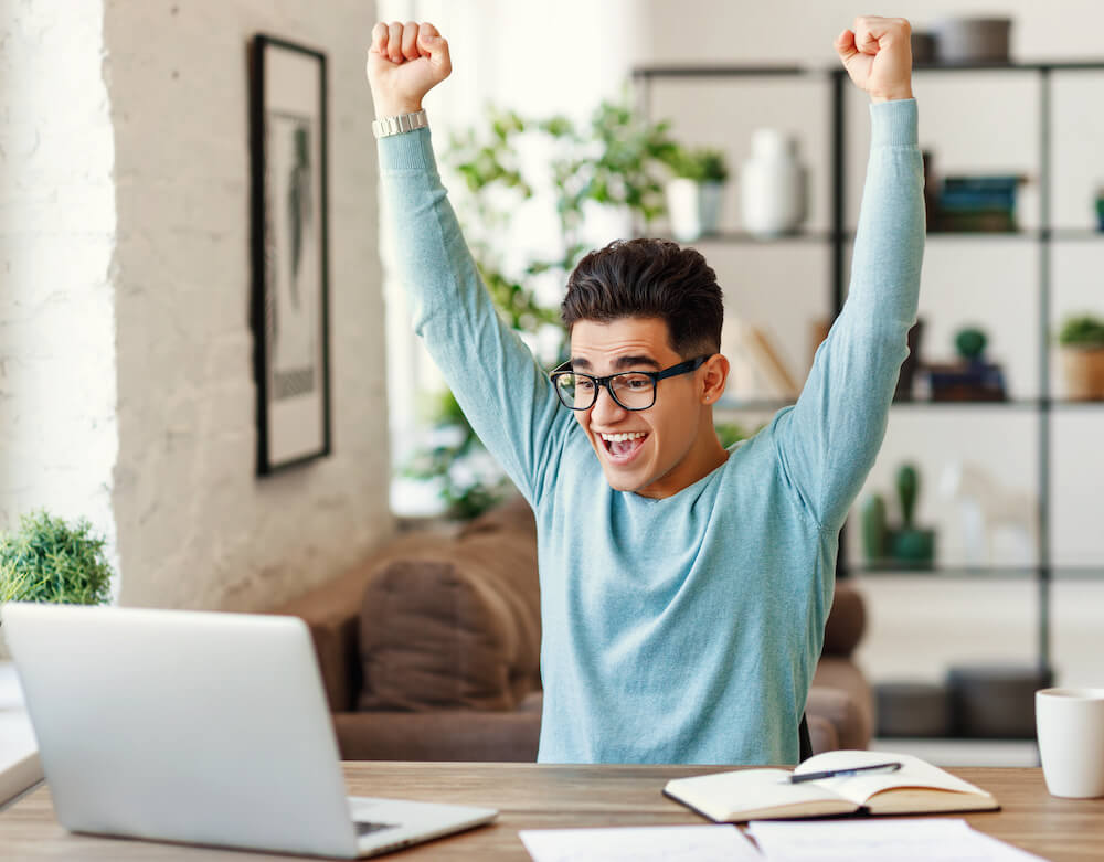 Happy graduate student with a certificate after graduation ceremony at the university. Student sitting at his laptop excited knowing his admission results for regular admission and early decision 2